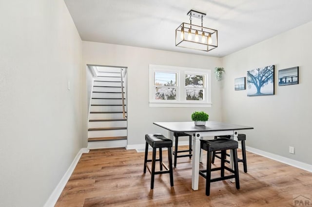 dining space with stairs, breakfast area, wood finished floors, and baseboards