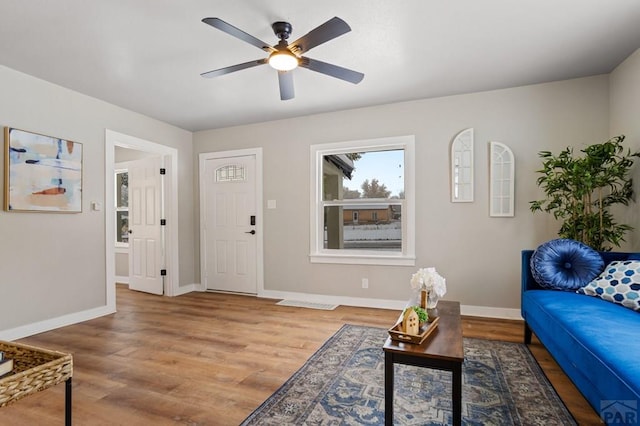 living room with wood finished floors, a ceiling fan, and baseboards