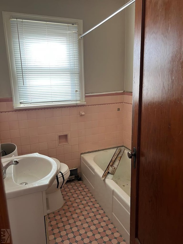 bathroom with wainscoting, tile walls, vanity, and a bath