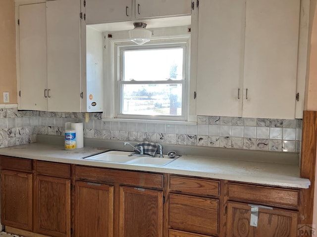 kitchen featuring brown cabinets, light countertops, a sink, and decorative backsplash