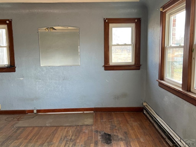 spare room with hardwood / wood-style floors, a baseboard radiator, baseboards, and a wealth of natural light