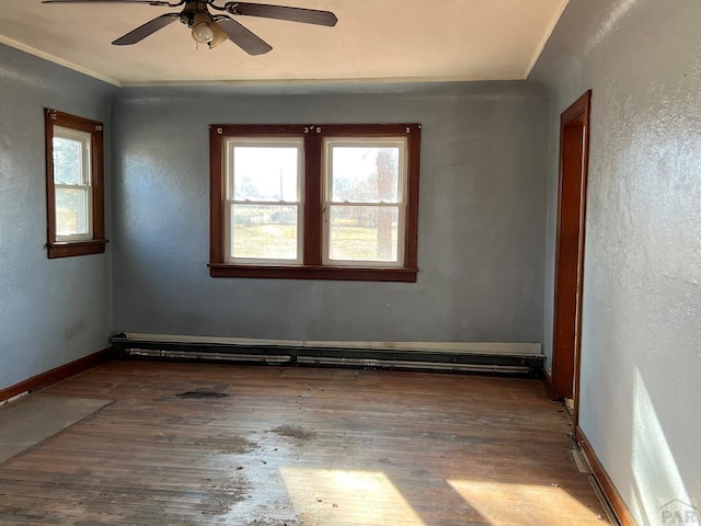 spare room featuring a baseboard radiator, wood finished floors, and a healthy amount of sunlight