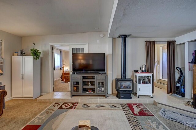 living area with light carpet, light tile patterned floors, and a wood stove