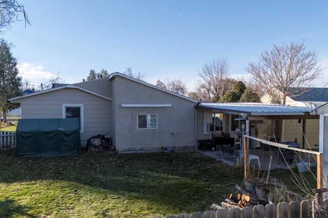 back of property with metal roof, a lawn, fence, and stucco siding