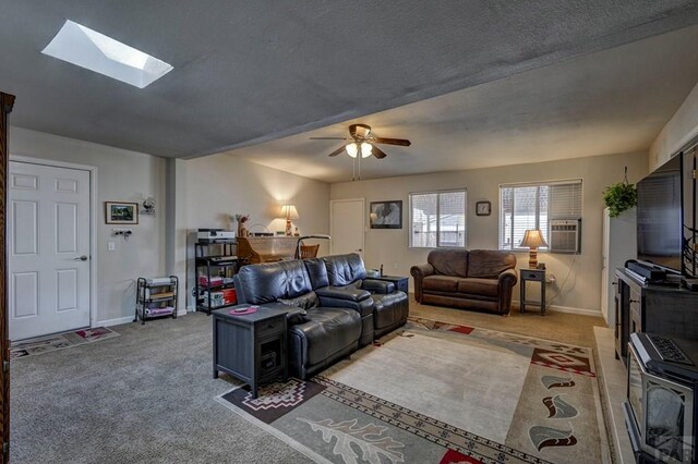 living room featuring light carpet, a skylight, baseboards, and a ceiling fan