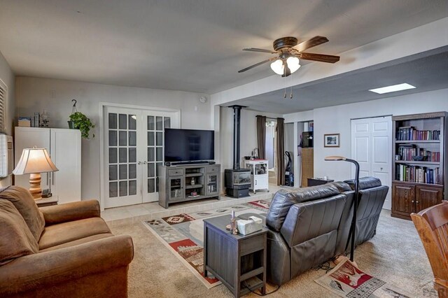 living area with french doors, light carpet, ceiling fan, and a wood stove