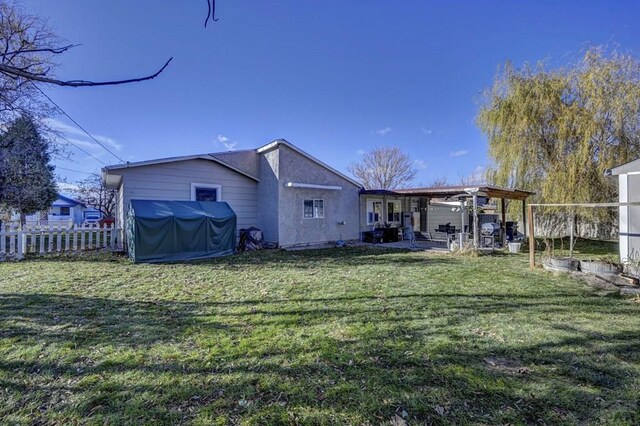 back of house with a patio, stucco siding, a lawn, fence, and a pergola