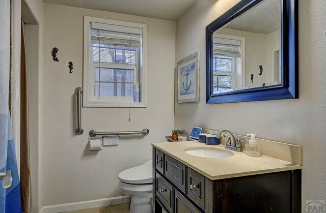 bathroom featuring a wealth of natural light, baseboards, vanity, and toilet