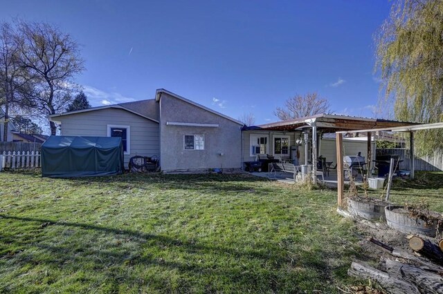 rear view of house with fence, a yard, a patio area, a pergola, and stucco siding