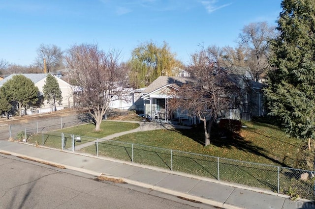 view of property hidden behind natural elements featuring a fenced front yard and a front lawn