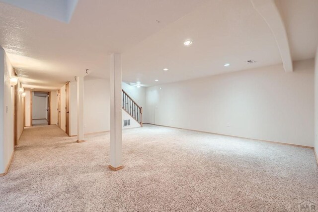 finished basement with recessed lighting, visible vents, light colored carpet, and stairway