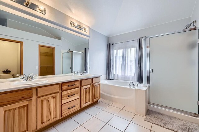 full bath featuring vaulted ceiling, a stall shower, tile patterned flooring, and a sink