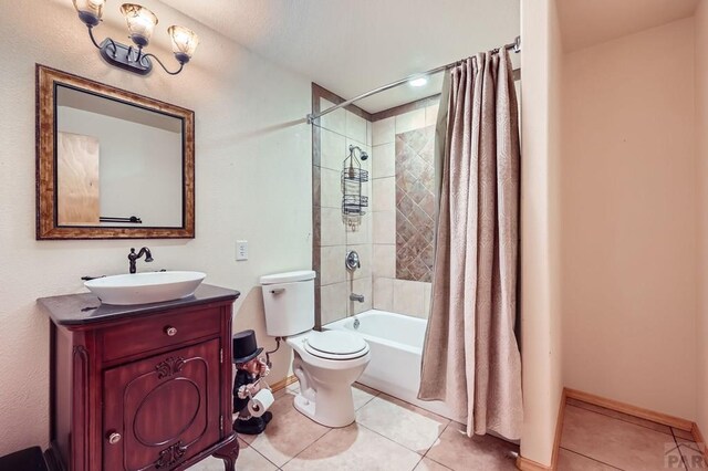 bathroom featuring toilet, vanity, baseboards, tile patterned floors, and shower / bath combo with shower curtain