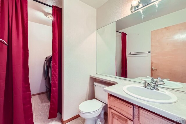 bathroom with toilet, washer / dryer, and vanity