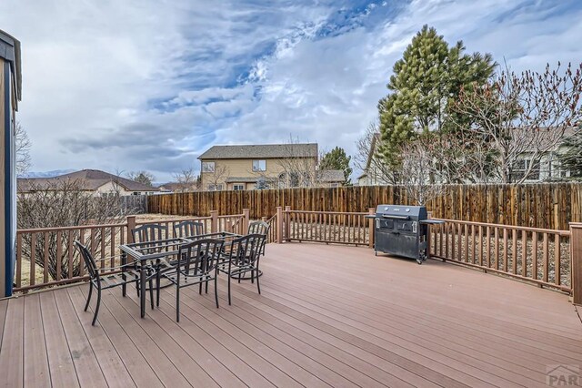 wooden terrace with a grill, a fenced backyard, and outdoor dining space