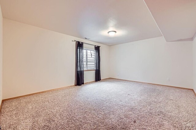 carpeted spare room with visible vents and baseboards