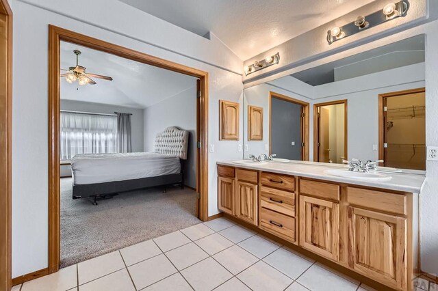 bathroom featuring lofted ceiling, connected bathroom, a sink, tile patterned floors, and double vanity