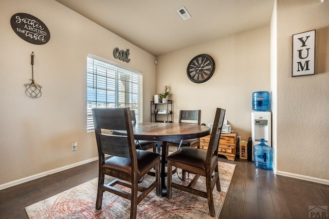 dining room with vaulted ceiling, dark wood-type flooring, visible vents, and baseboards