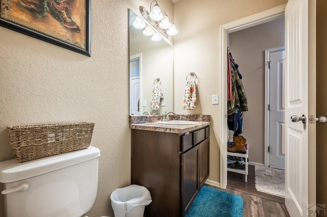 bathroom featuring baseboards, vanity, toilet, and wood finished floors