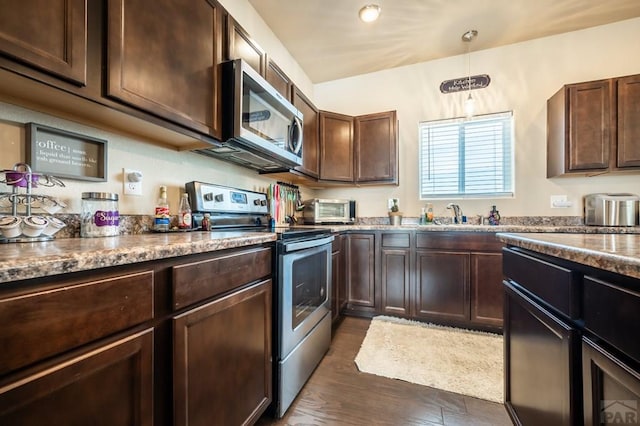 kitchen with dark stone counters, dark brown cabinets, and appliances with stainless steel finishes