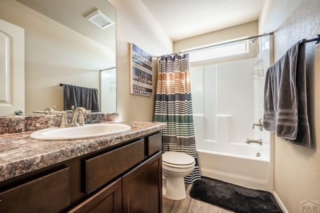 full bath with visible vents, toilet, wood finished floors, shower / bath combo with shower curtain, and vanity