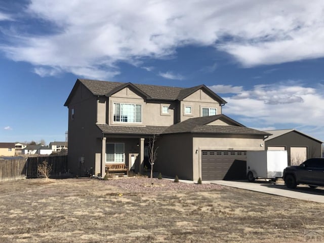 view of front of house with stucco siding, driveway, a garage, and fence