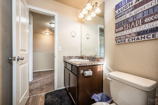 bathroom with toilet, baseboards, wood finished floors, and vanity