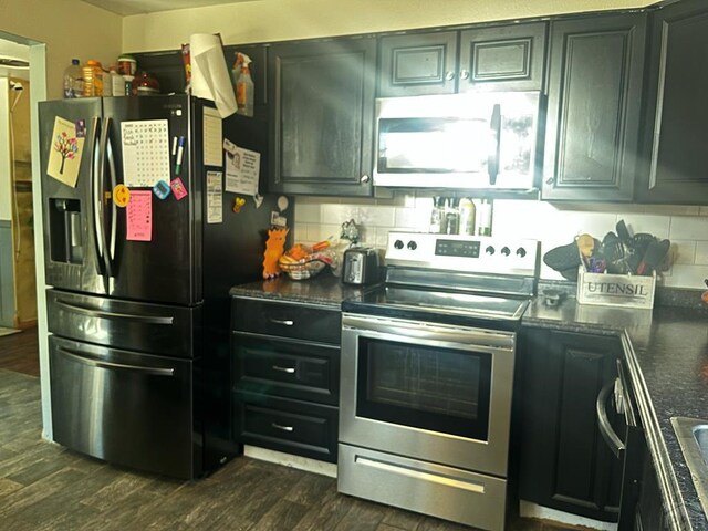kitchen with dark cabinetry, decorative backsplash, dark wood-style floors, and appliances with stainless steel finishes