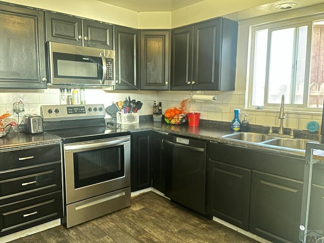 kitchen with dark wood-style floors, a sink, appliances with stainless steel finishes, and tasteful backsplash