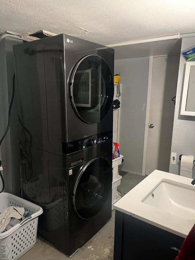 clothes washing area with stacked washer and dryer, a sink, and a textured ceiling