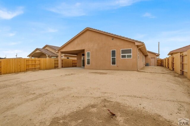 rear view of house featuring a fenced backyard and stucco siding