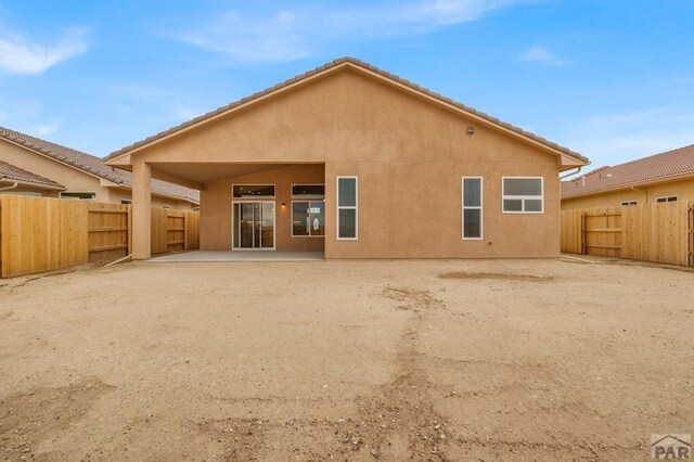 rear view of property with a fenced backyard, a patio, and stucco siding