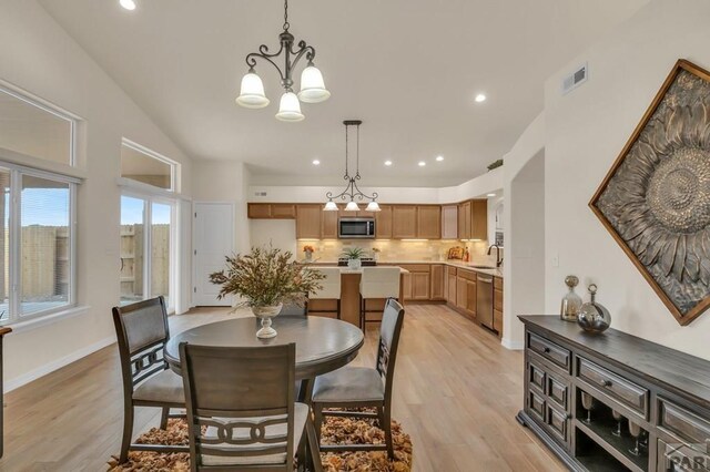 dining area with a chandelier, light wood finished floors, visible vents, and baseboards