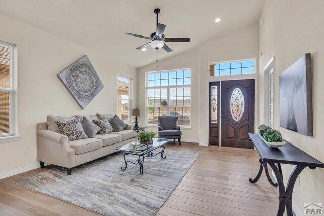 living area with light wood-style floors, recessed lighting, high vaulted ceiling, and baseboards