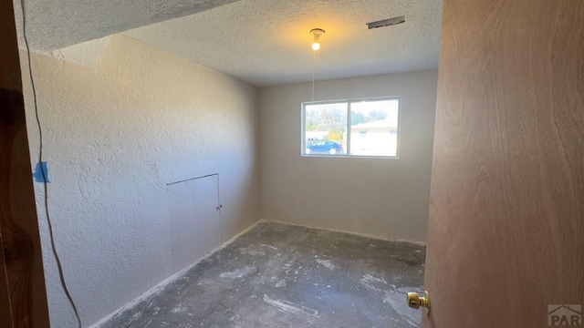 empty room with a textured ceiling and a textured wall