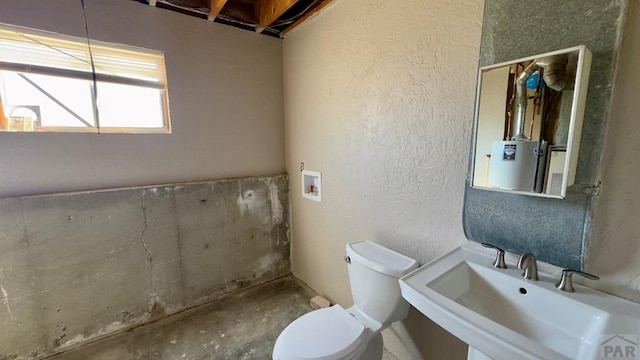 bathroom with a textured wall, a sink, and toilet