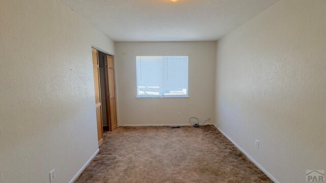 unfurnished room with light carpet and baseboards