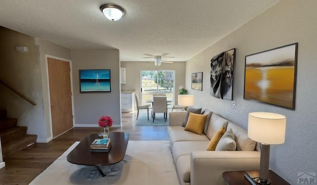 living area with a textured ceiling, stairway, wood finished floors, and a textured wall