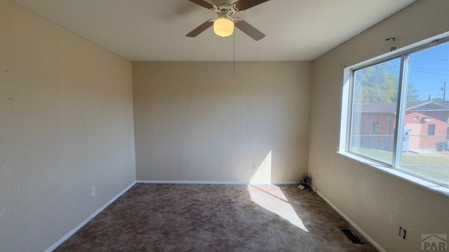 unfurnished room with ceiling fan, baseboards, visible vents, and dark colored carpet