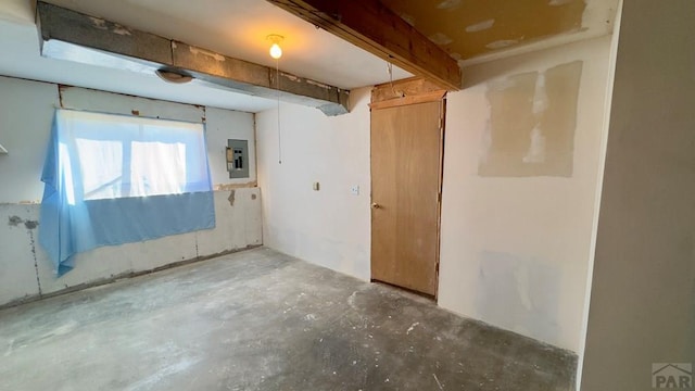 spare room featuring electric panel and unfinished concrete flooring