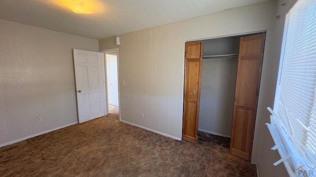 unfurnished bedroom featuring a closet, dark carpet, and baseboards