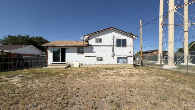 rear view of house with a fenced backyard and a lawn