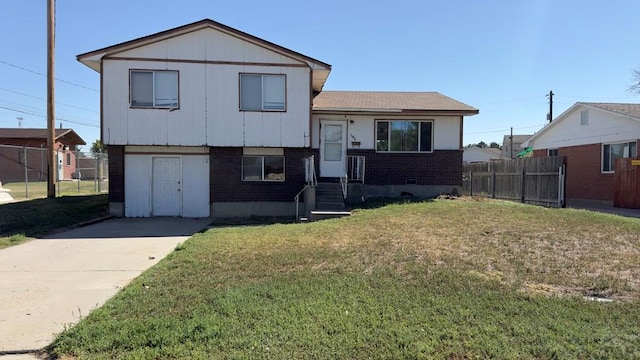 tri-level home with a front yard, fence, and brick siding