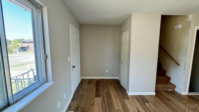 interior space with light wood-style flooring, baseboards, and a textured ceiling