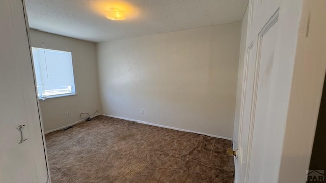 spare room featuring a textured ceiling, carpet flooring, visible vents, and baseboards