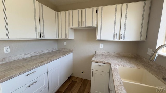 kitchen with dark wood-style floors, white cabinetry, and a sink