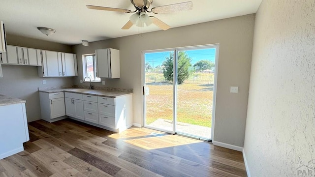 kitchen with light countertops, white cabinets, baseboards, and wood finished floors