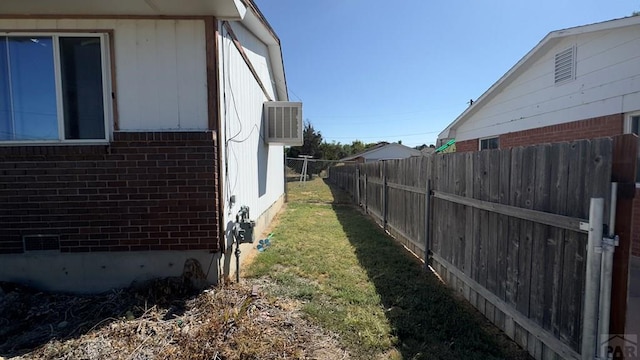 view of side of property featuring fence, a lawn, and brick siding