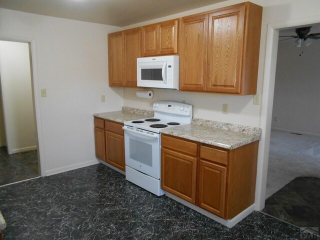 kitchen featuring brown cabinetry, white appliances, baseboards, and a ceiling fan