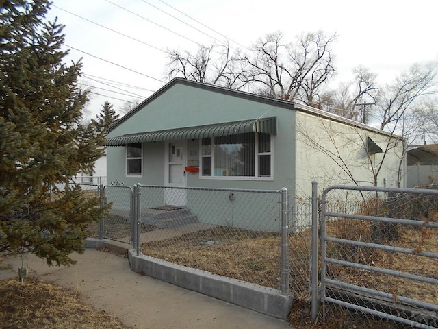 view of front facade featuring a fenced front yard, a gate, and stucco siding